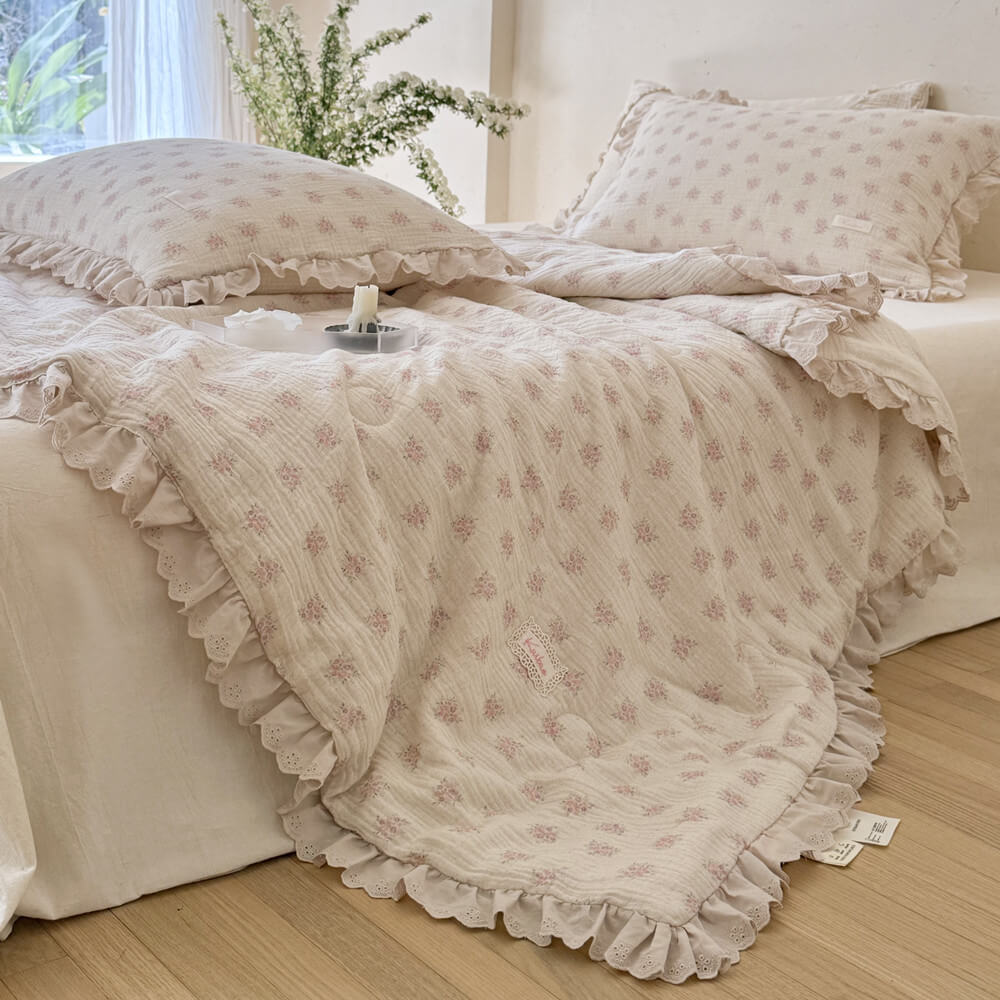 Pink floral comforter with soft ruffled lace trim styled in a bright cottage bedroom