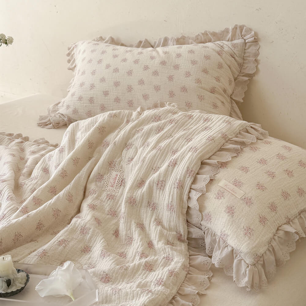 Pink floral comforter layered with matching styled pillows and soft ivory lace details