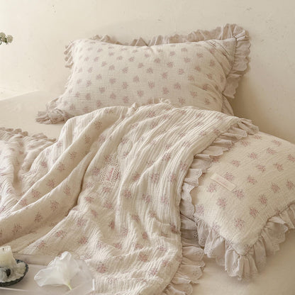 Pink floral comforter layered with matching styled pillows and soft ivory lace details