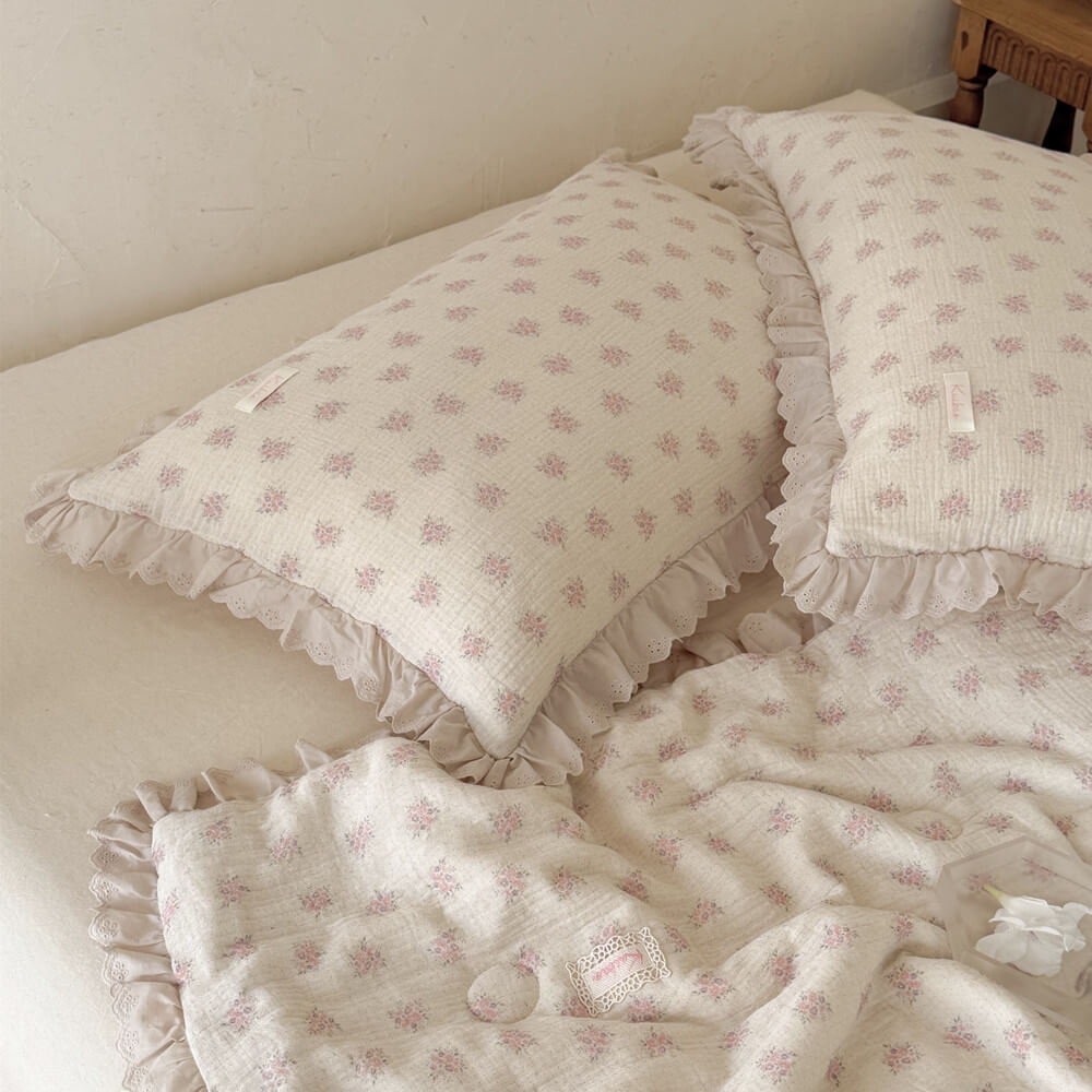 Pink floral cotton comforter and ruffled pillows styled in a relaxed romantic bedroom