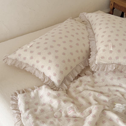 Pink floral cotton comforter and ruffled pillows styled in a relaxed romantic bedroom