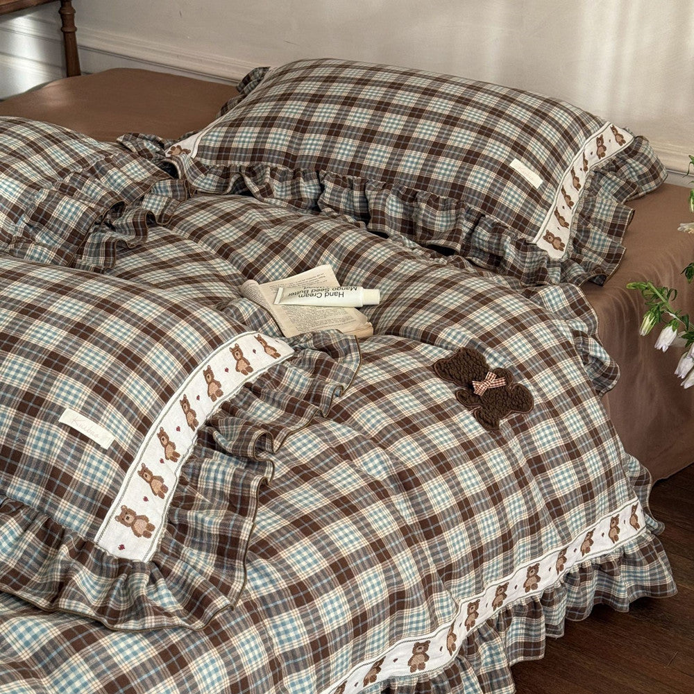 Plaid bedspread with teddy bear designs on a bed in a bedroom setting.