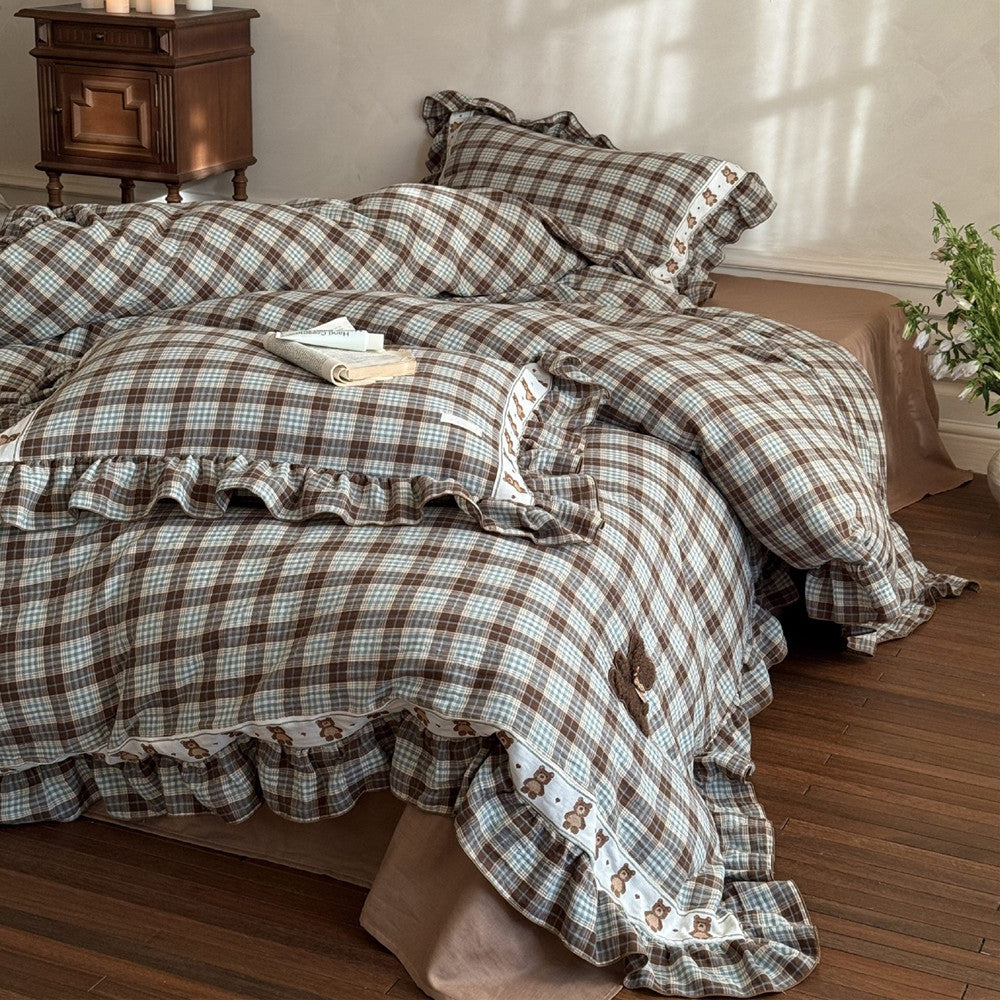 Plaid bedspread with ruffled edges on a bed in a bedroom setting.