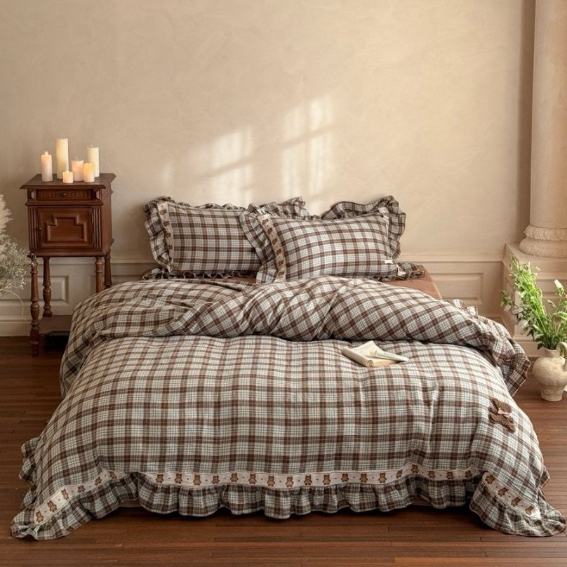 Plaid bedspread set on a bed in a bedroom with wooden nightstand and decor.