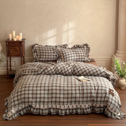 Plaid bedspread set on a bed in a bedroom with wooden nightstand and decor.
