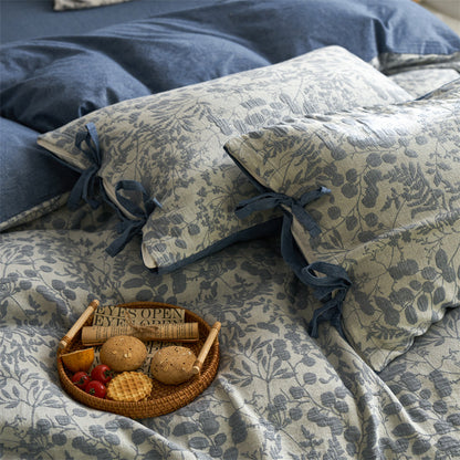 Close-up of slate blue floral jacquard pillows and duvet with tie closures and breakfast tray detail.