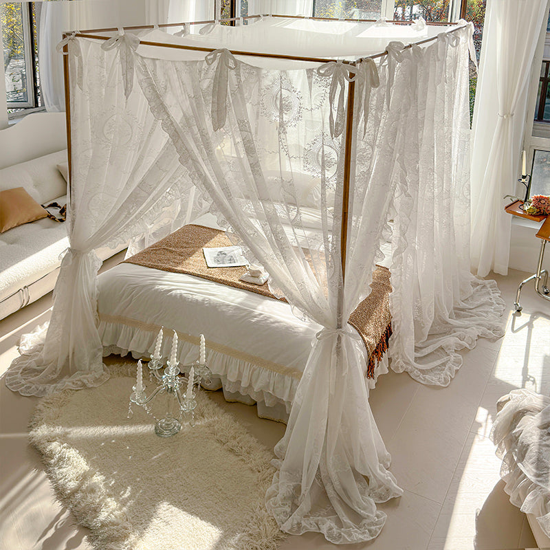 Romantic bedroom with white floral lace bed canopy curtains, cozy bedding, and natural light