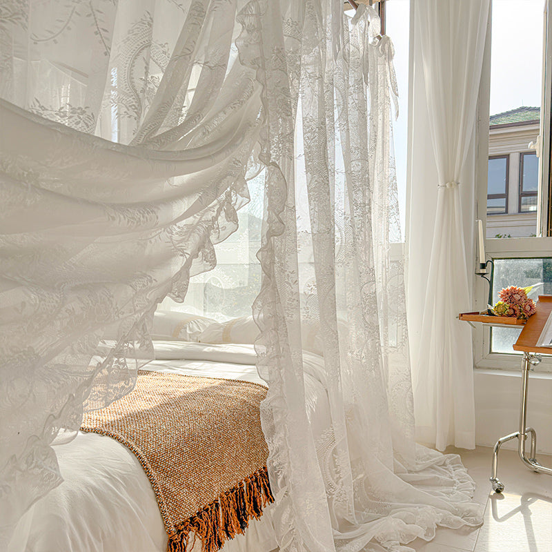 Elegant bedroom with white floral lace bed canopy, cozy blanket, and natural light