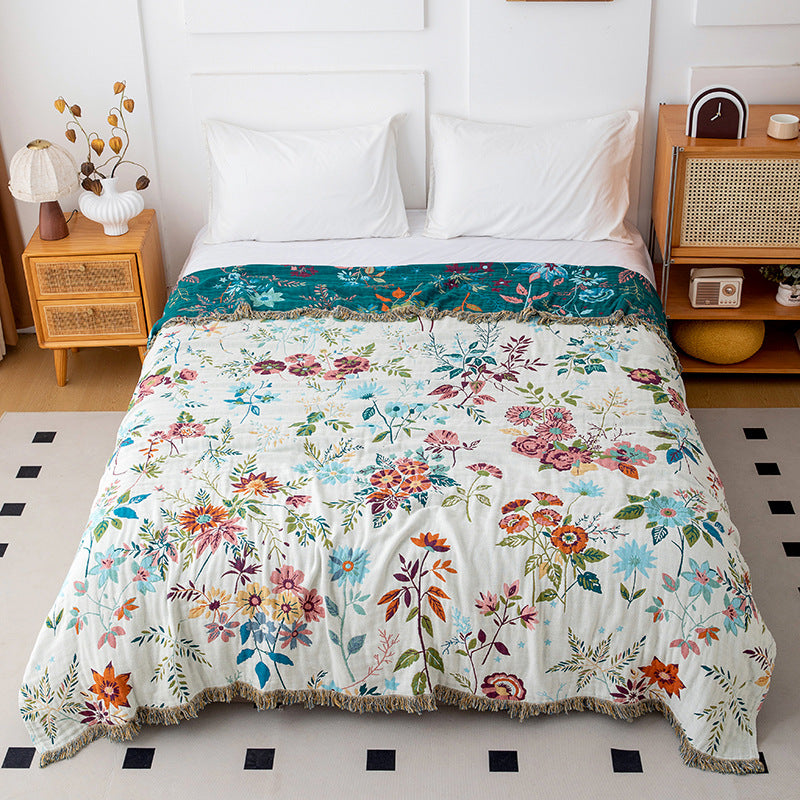 Reversible botanical cotton throw blanket showing ivory floral side on a white bed