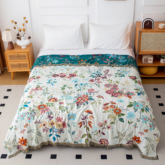 Reversible botanical cotton throw blanket showing ivory floral side on a white bed