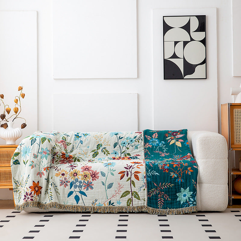 Reversible cotton botanical throw blanket draped over sofa showing ivory and teal sides