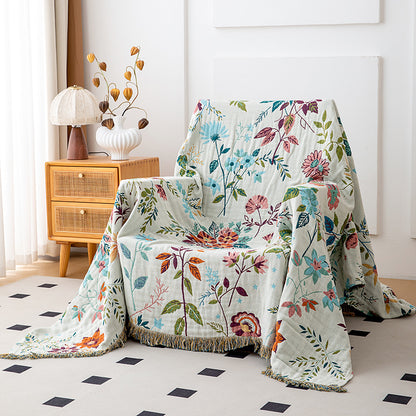 Ivory botanical cotton throw blanket with fringe styled over an accent chair