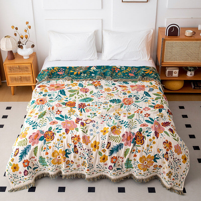 Reversible floral cotton throw blanket with ivory side styled on a white bed