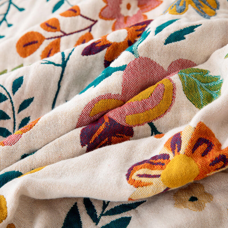Close-up of reversible floral cotton throw blanket with warm pink and mustard flower details