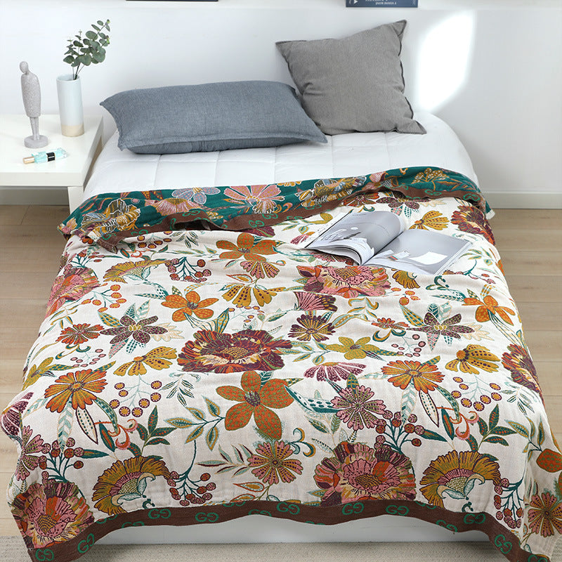 Close-up of the intricate floral print on a reversible autumn throw blanket with a magazine resting on its textured woven surface.