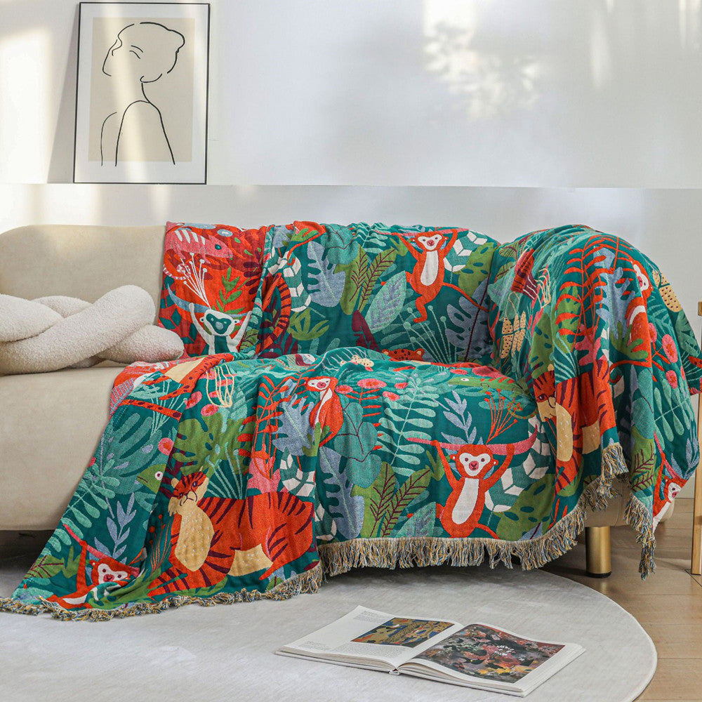 Jungle Animal Cotton Jacquard Throw Blanket styled on a beige sofa, covering the seat and back with a colorful tropical tiger and monkey design to add a decorative accent to the living room.