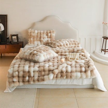 A full view of a bed with a light brown and white tie-dye patterned faux rabbit fur blanket and multiple matching pillows, creating a cozy and luxurious look.