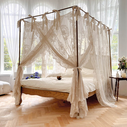 Romantic lace bed canopy curtain with ties over natural wood bed in bright, airy bedroom