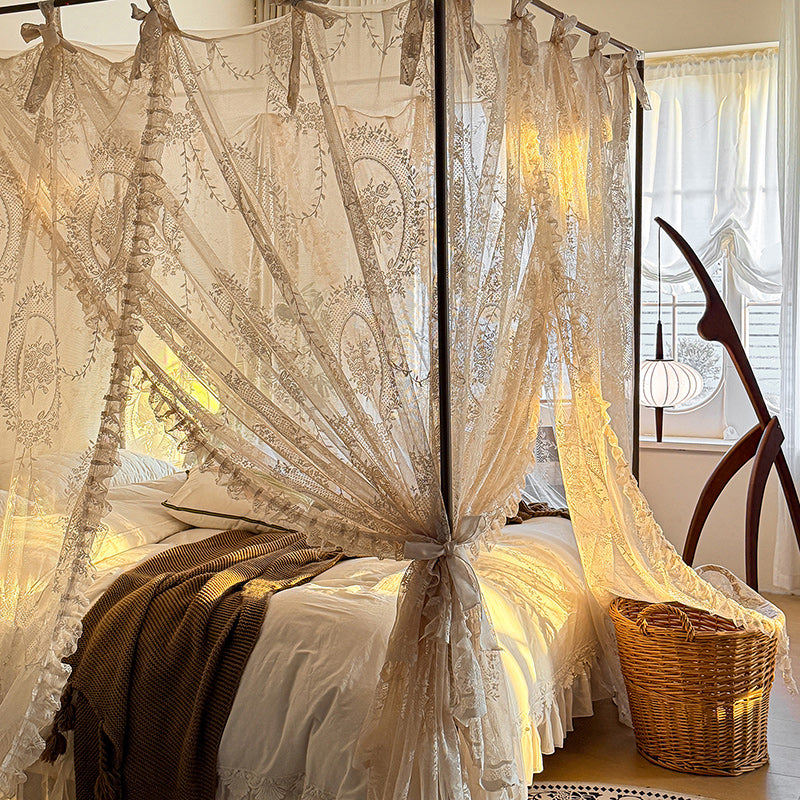 Romantic lace bed canopy curtains on a four-poster bed with cozy bedding in a sunlit bedroom.