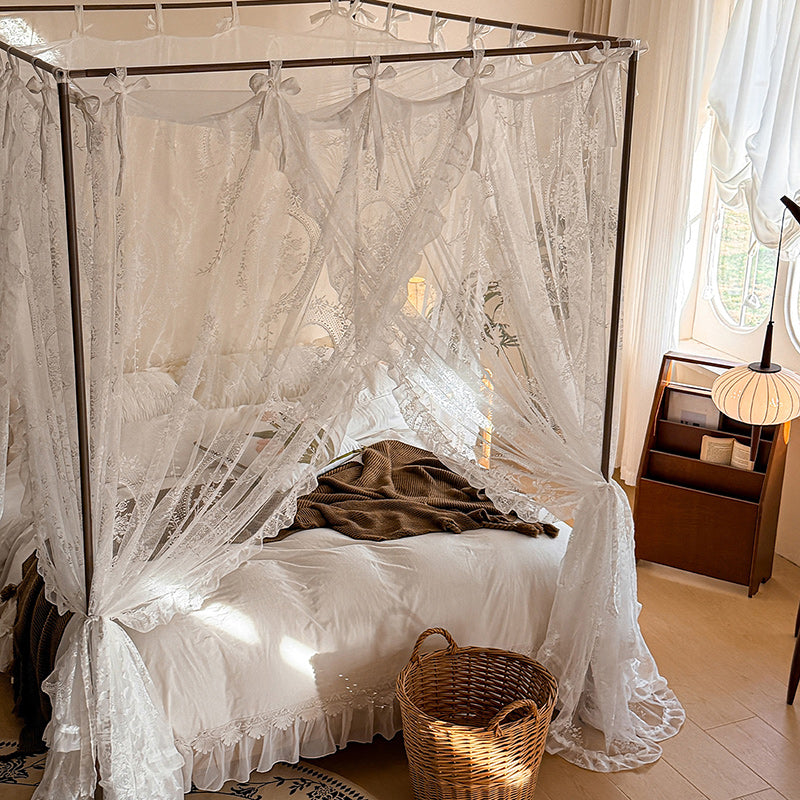 Romantic lace canopy curtains on a four-poster bed in a cozy, sunlit bedroom