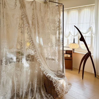 Lace canopy bed in a bedroom with a lamp and window in the background