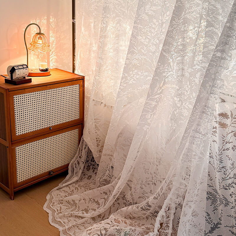 Floral lace curtain with wooden cabinet and lamp in the background