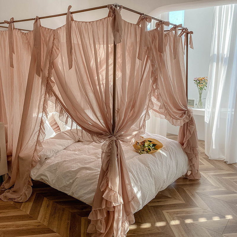 Romantic ruffled pink canopy curtains on a four-poster bed with soft cotton bedding
