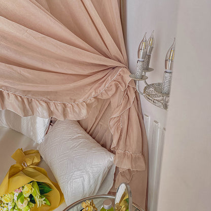 Romantic ruffled canopy curtains on 4-poster bed with white cotton bedding and flowers