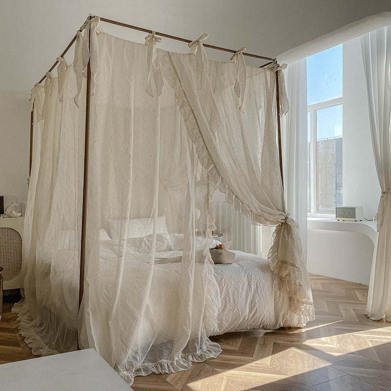 Romantic ruffled canopy curtains on 4-poster bed with pure cotton bedding in sunlit bedroom