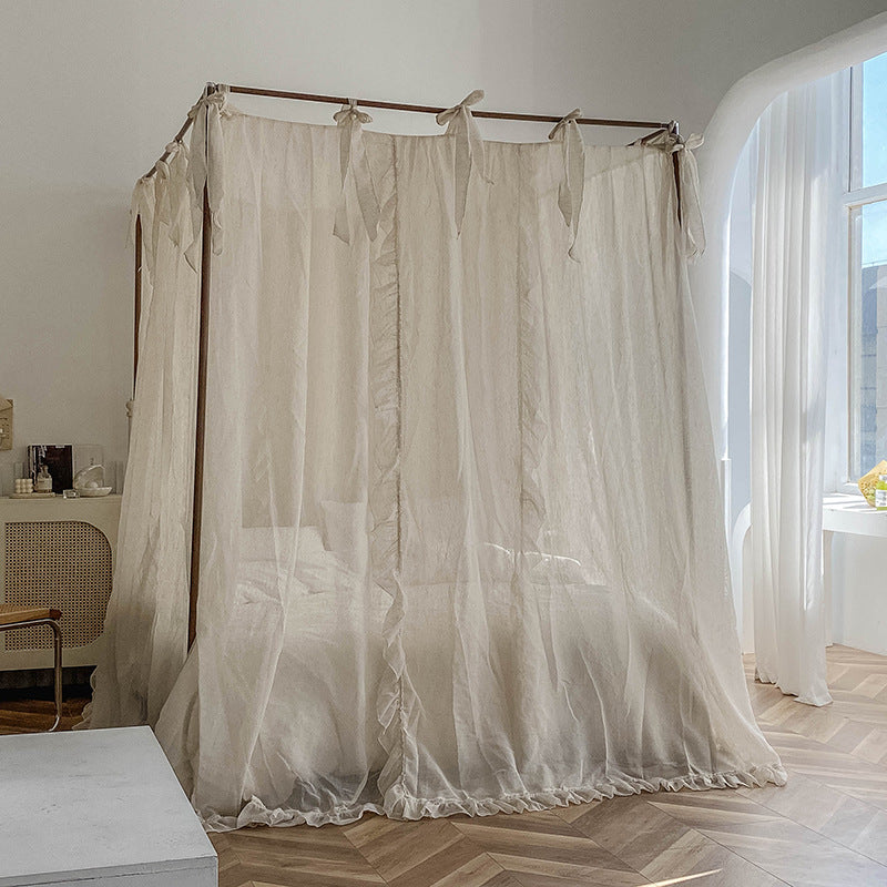 Romantic ruffled canopy curtains on a 4-poster bed in a sunlit bedroom