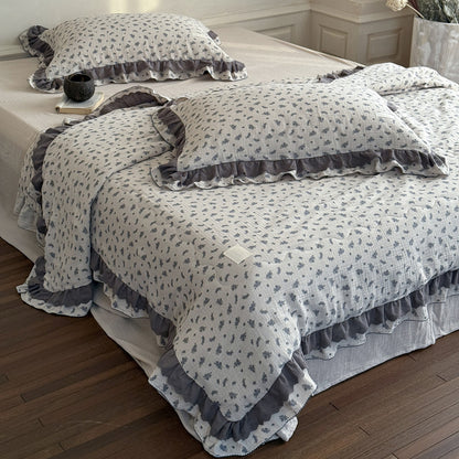 Floral patterned comforter set with ruffled edges on a bed in a bedroom.