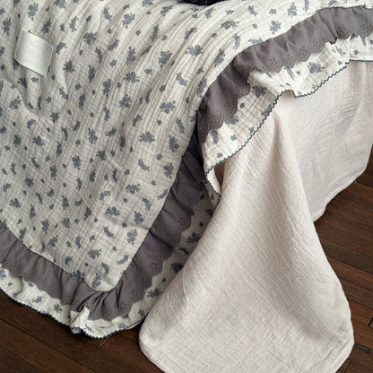 Detail view of ruffled edge and floral pattern on lightweight comforter