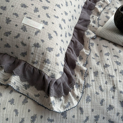 Detail view of ruffled edge and floral pattern on pillowcase and  lightweight comforter