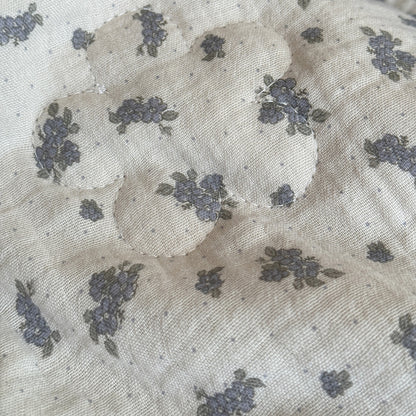 Close-up of dusty blue floral comforter with flower-shaped quilting
