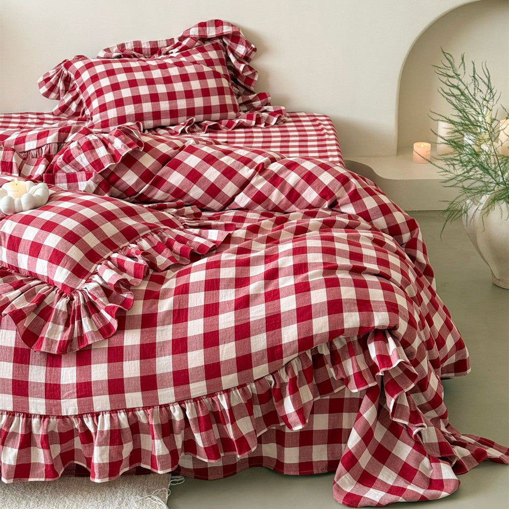 Red and white checkered bedspread with ruffles on a bed in a bedroom setting.