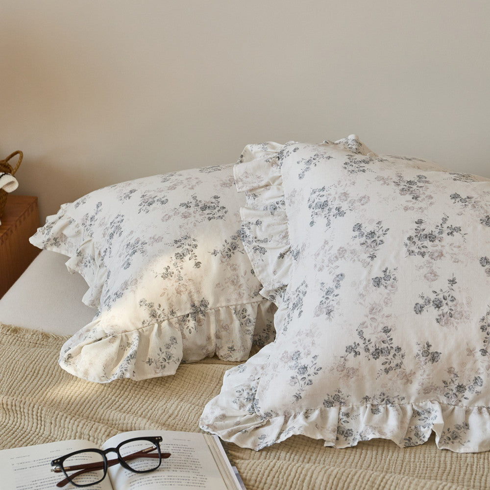 Detailed close-up of soft floral cotton muslin fabric with elegant ruffle edges on decorative pillow shams