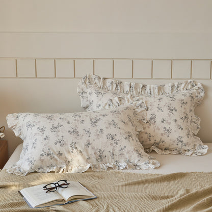 Romantic floral cotton muslin pillow shams with ruffle detailing, showcased on a neutral-toned bed setup