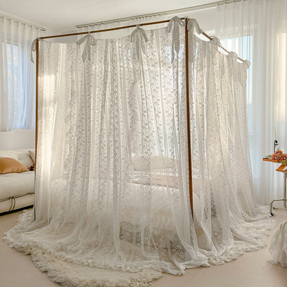 Sheer lace bed canopy on four-poster bed in bright, modern bedroom with soft natural light