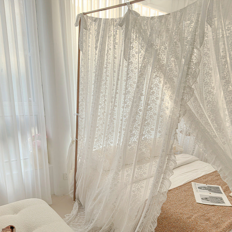Sheer lace bed canopy in bright bedroom with natural light and white cotton bedding