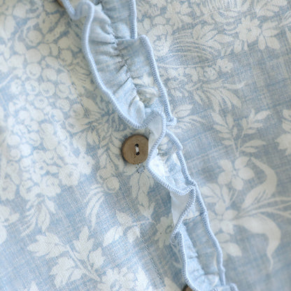 Close-up of soft blue ruffled floral cotton pajama set with wooden button detail