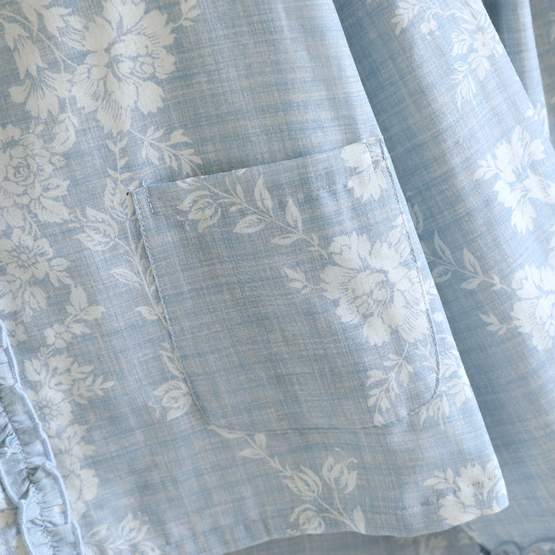 Soft blue cotton pajama set with white floral print, ruffled trim, and front pocket detail