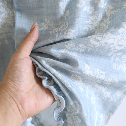 Hand holding soft blue ruffled cotton pajama set with white floral print
