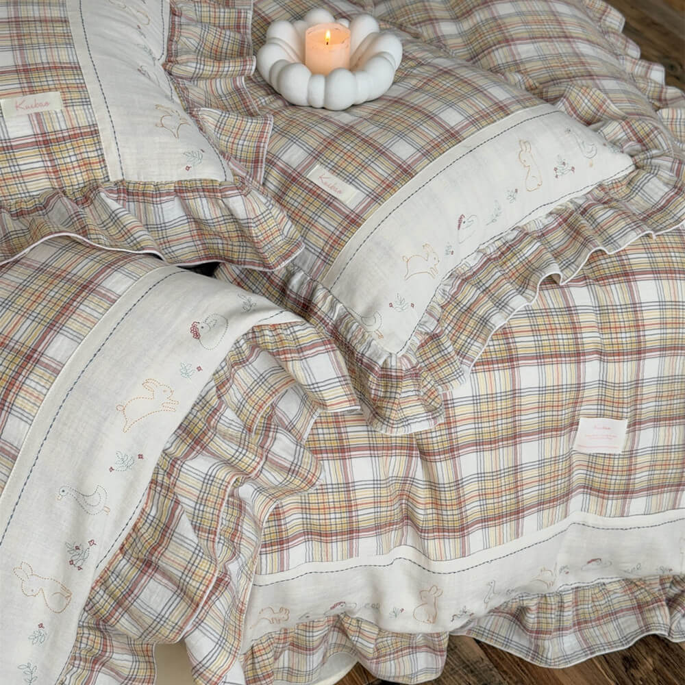 Close-up of plaid bedding set, showing ruffled trim and fine embroidery on cotton muslin
