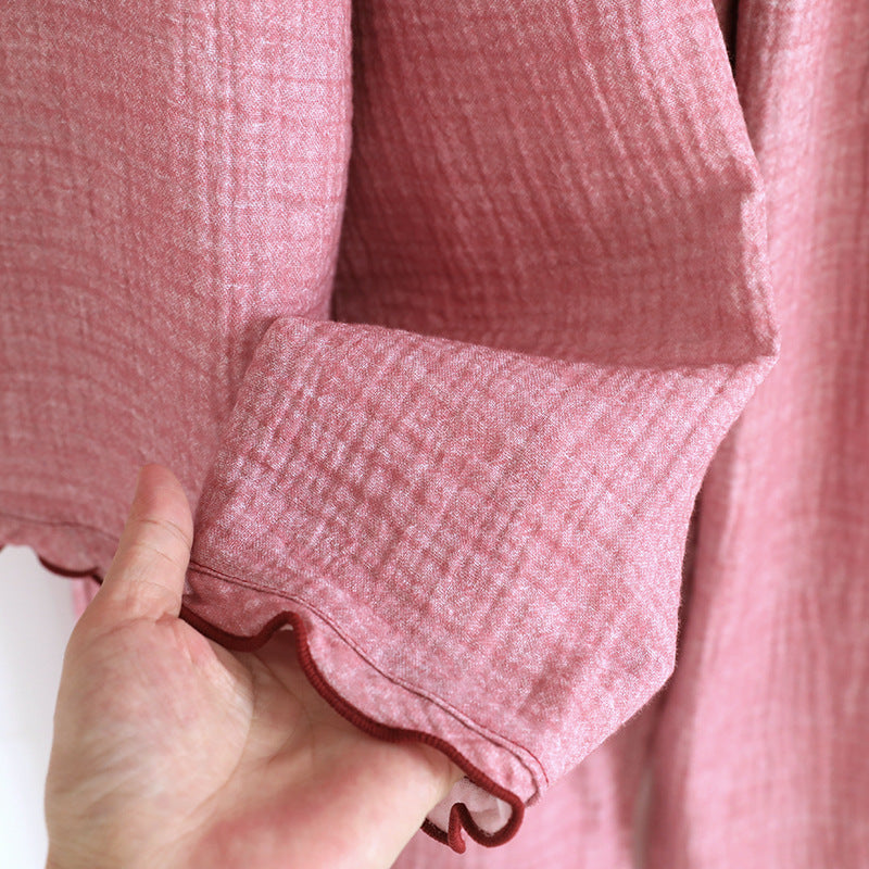 Soft pink cotton gauze pajama sleeve with ruffled edge held by a hand
