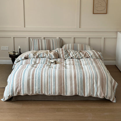 Striped cotton gauze bedding set in soft blue and beige tones on a cozy bed in a minimalist bedroom