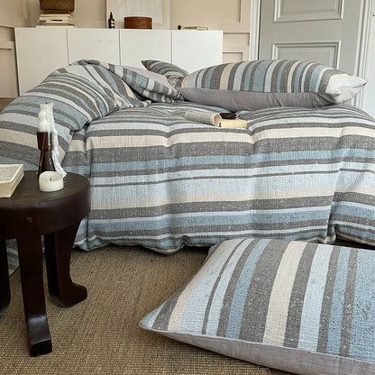 Striped cotton gauze bedding set with blue, gray, and beige tones on cozy bed with matching pillows