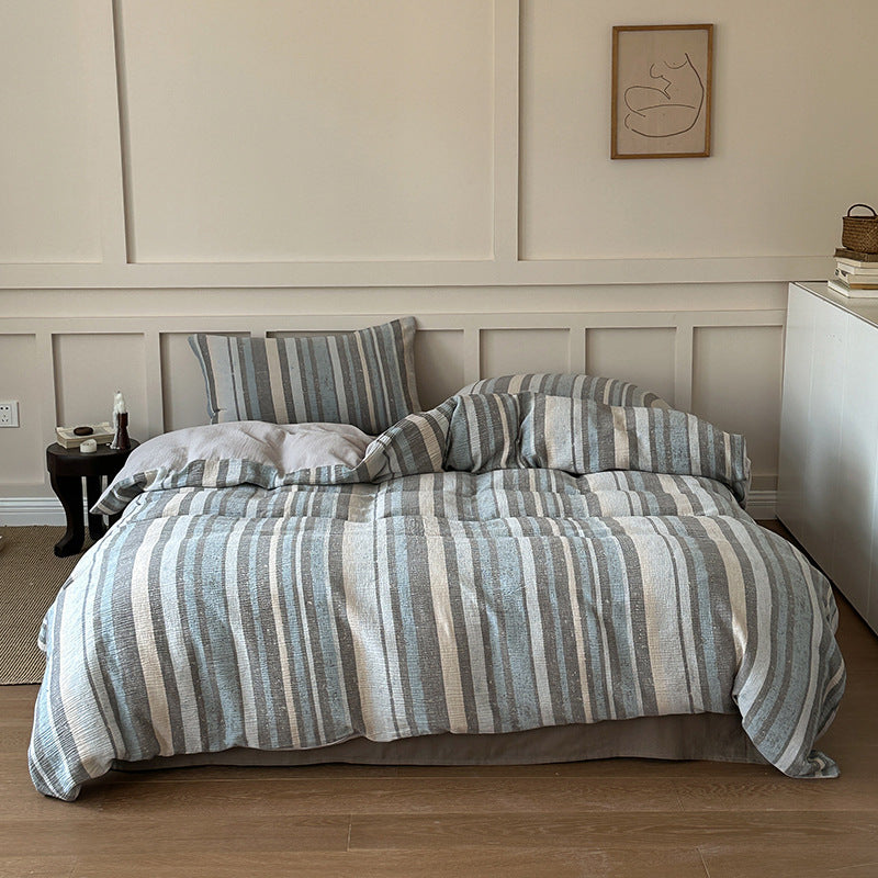 Cozy bedroom with striped cotton gauze bedding set in grey and beige, natural sustainable fabric
