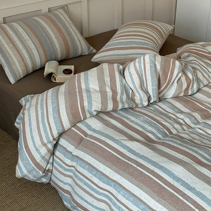 Striped cotton gauze bedding set with blue, beige, and white stripes on cozy bed with open book