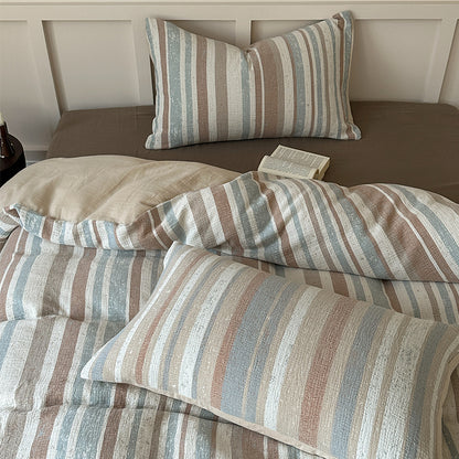 Striped cotton gauze bedding set with blue, beige, and white tones on a brown fitted sheet, open book on bed