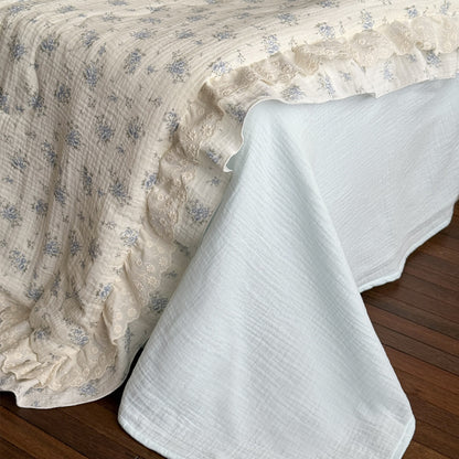 Blue floral cotton comforter with ruffled trim and gauze bed sheet